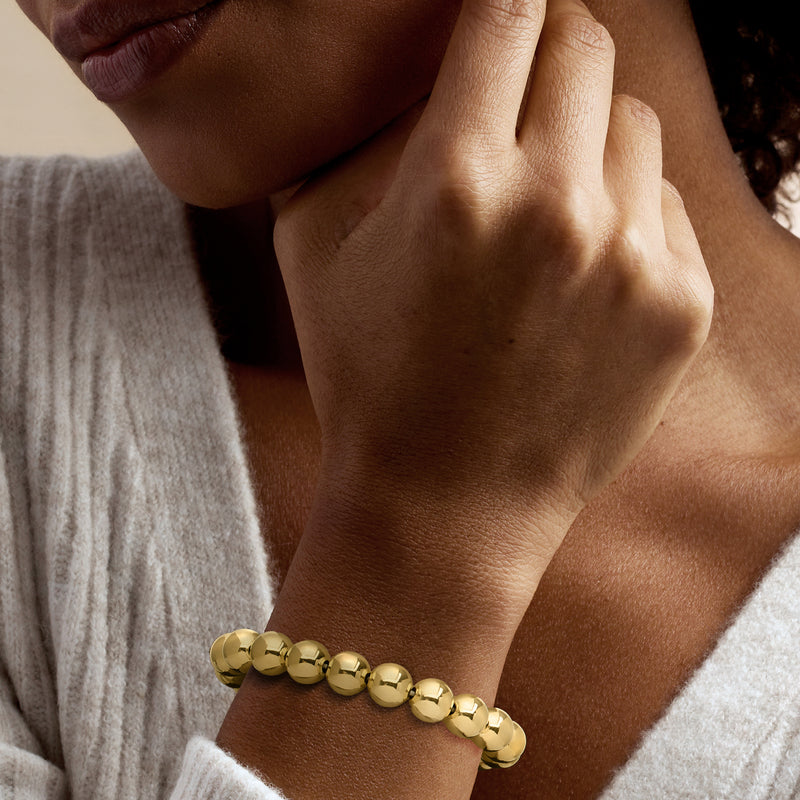 Gold tone bead stretch bracelet on wrist, round beads