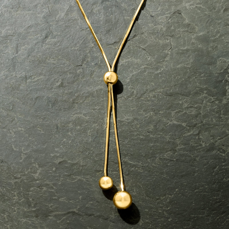 Gold over sterling lariat necklace with round top clasp and two dangling bead drops