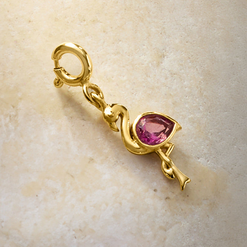 Gold charm with pink teardrop topaz and small flamingo detail, viewed from the side