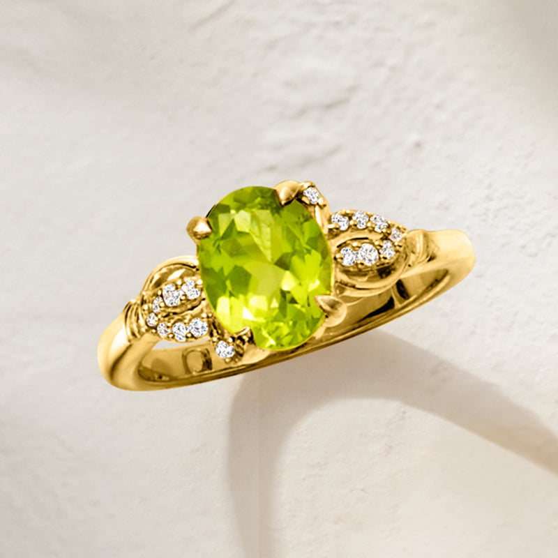 Gold ring with oval peridot-green center stone and white zircon clusters, angled view