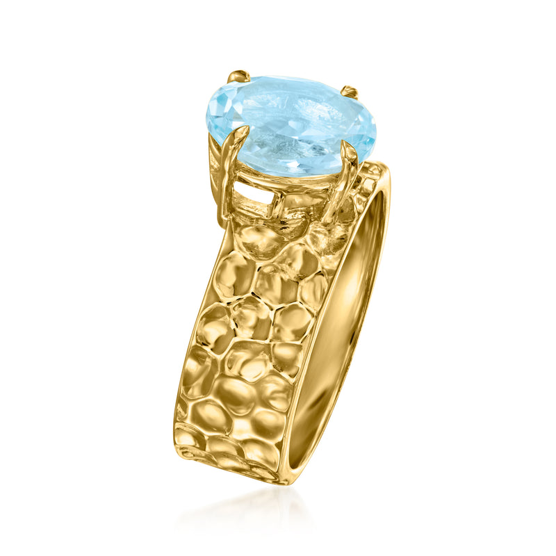 Gold oval gemstone ring with textured wide band and blue stone prongs