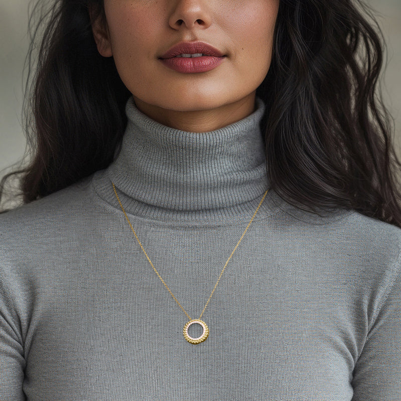 Gold chain necklace with round diamond halo pendant centered on neckline