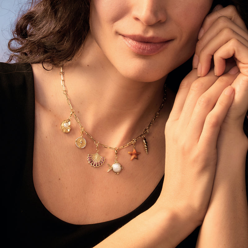 Gold paper-clip link toggle necklace with mixed dangle charms, including star