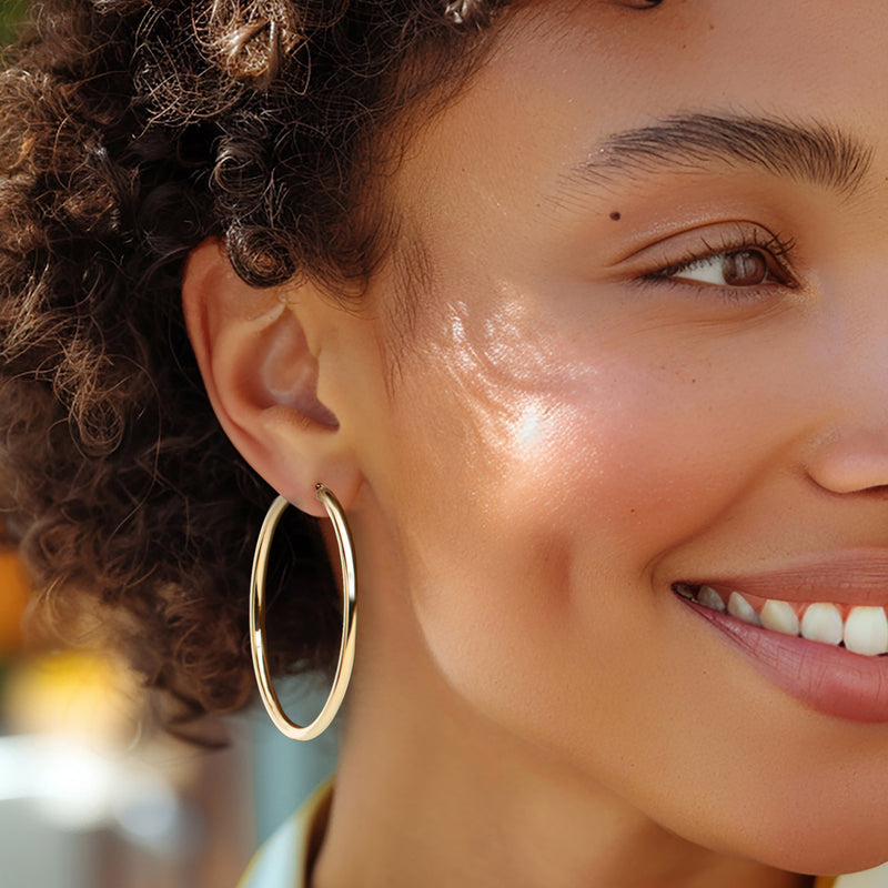 Thin 14kt yellow gold hoop earring on ear, smooth oval hoop