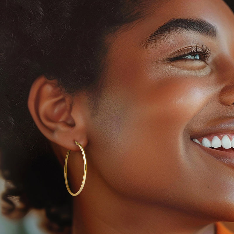 Small yellow gold hoop earrings on ear, round hinged style