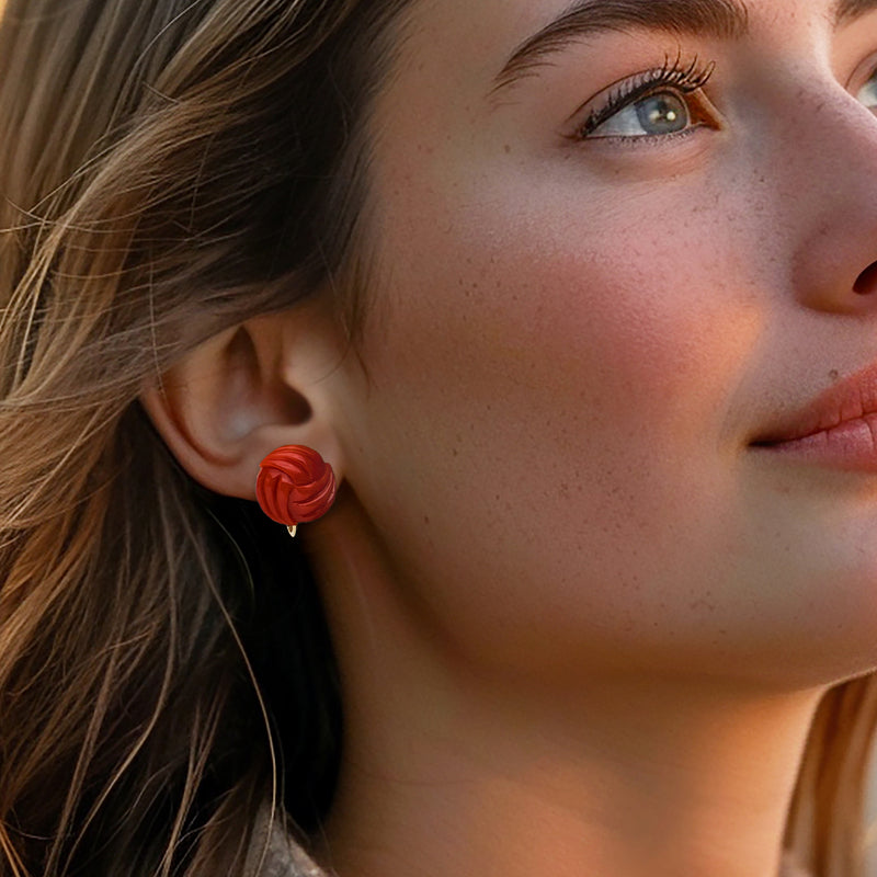 Red coral love-knot clip earrings on model, round swirl coral with yellow gold backs