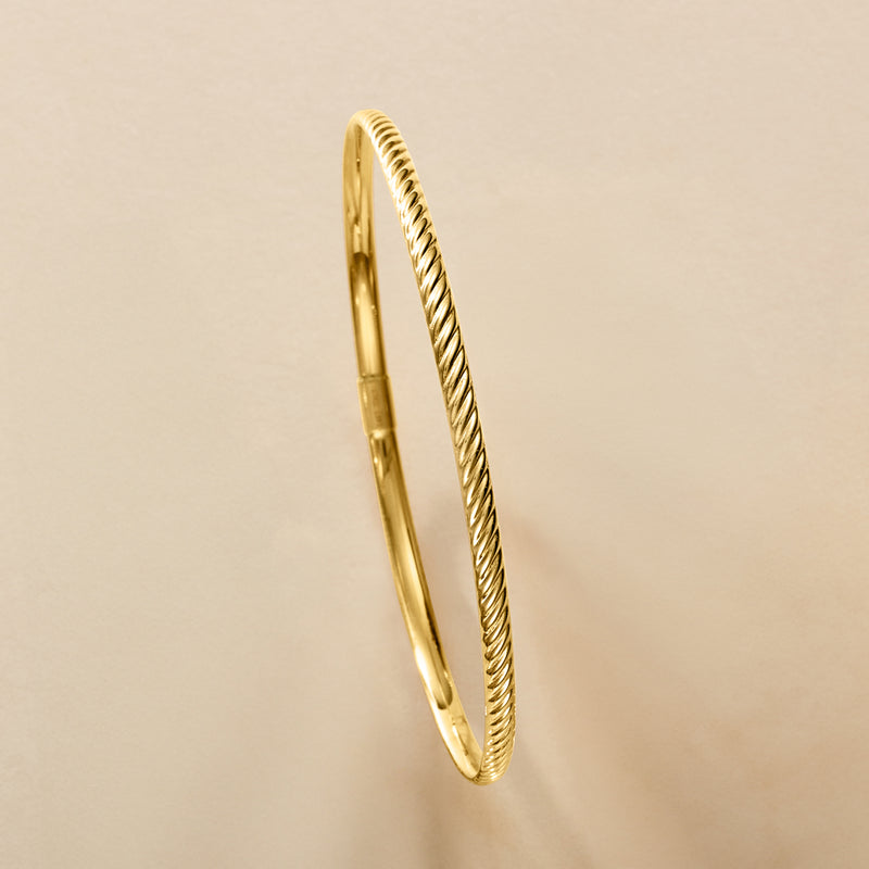 Yellow gold ridged bangle bracelet with clasp and braided rope detail along edge