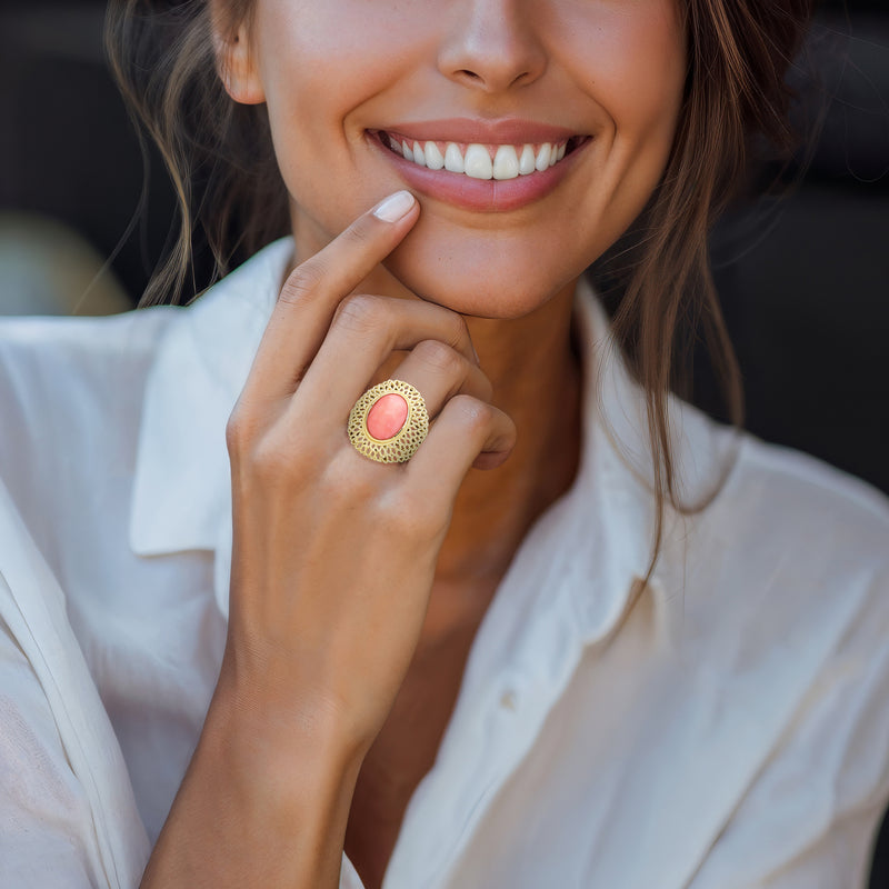 Gold coral dome ring with oval pink center on finger, scalloped openwork design