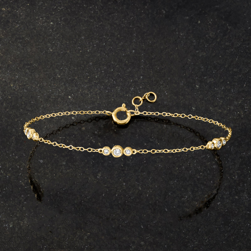 Yellow gold chain bracelet with graduated bezel-set round diamonds and spring clasp.