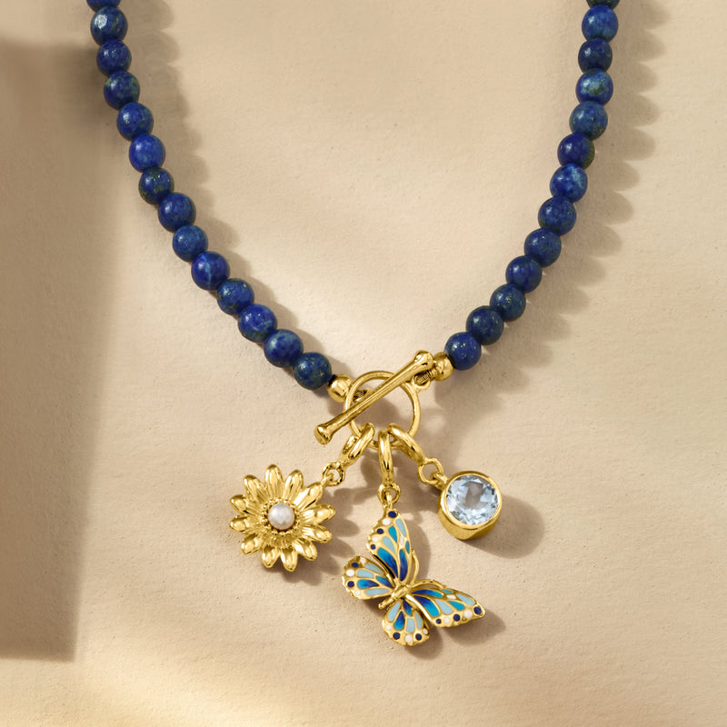 Gold charm cluster with sunflower charm, round white cultured pearl, and blue butterfly detail