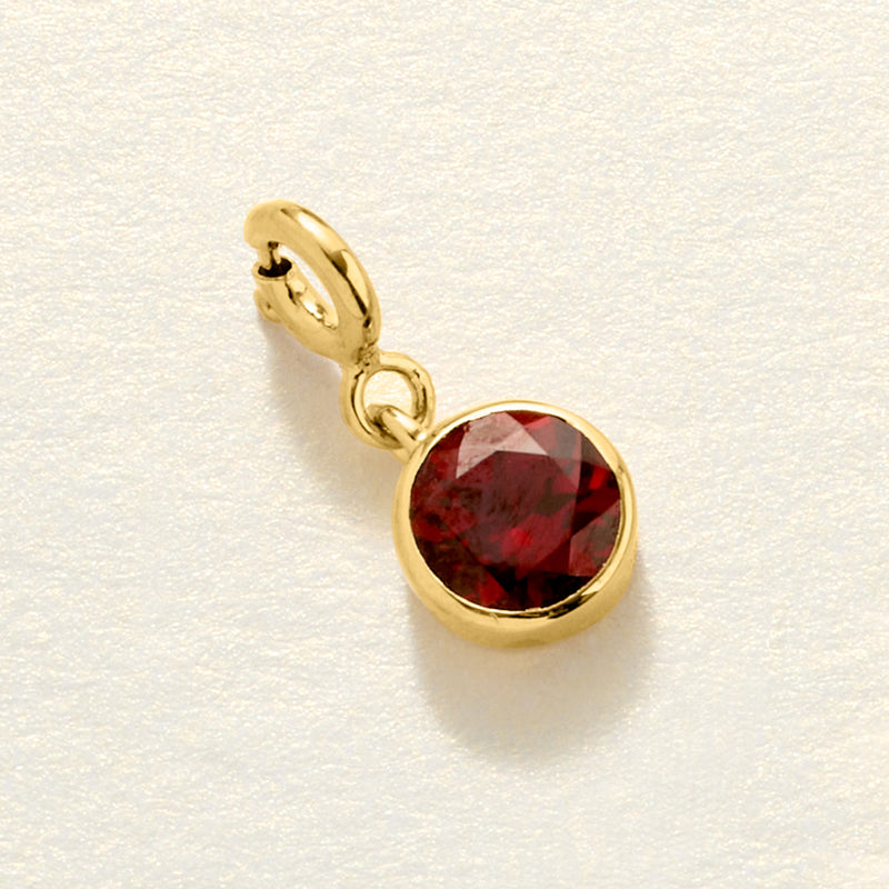 Gold-tone round red birthstone charm pendant with faceted center