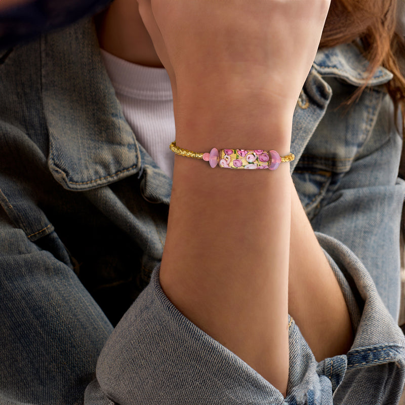 Pink floral bead wrap bracelet worn on wrist with gold-tone chain and small pink charm