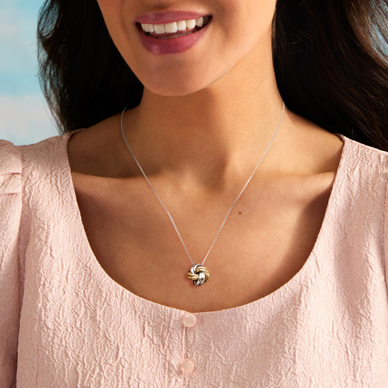 Love knot necklace with small gold accent pendant on fine silver chain, worn at neckline