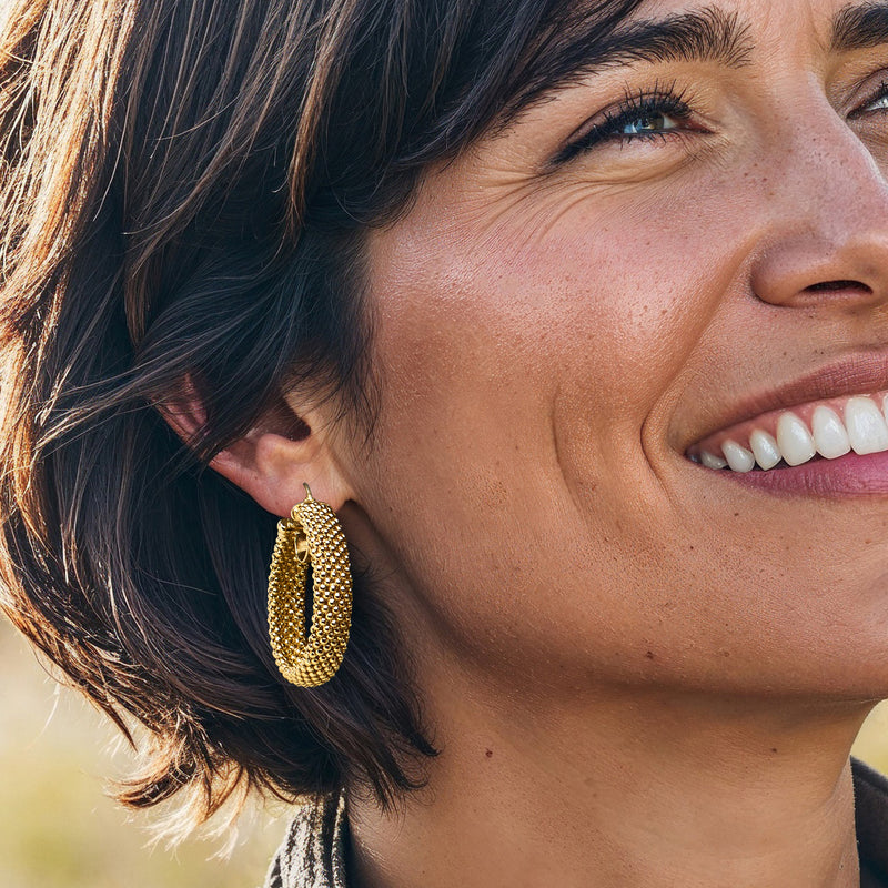 Gold popcorn-textured hoop earring close-up, oval beaded pattern