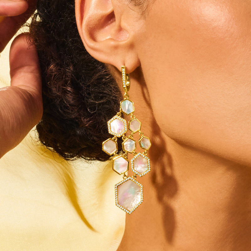 Gold drop chandelier earrings on the ear with mother-of-pearl and white topaz geometric stones