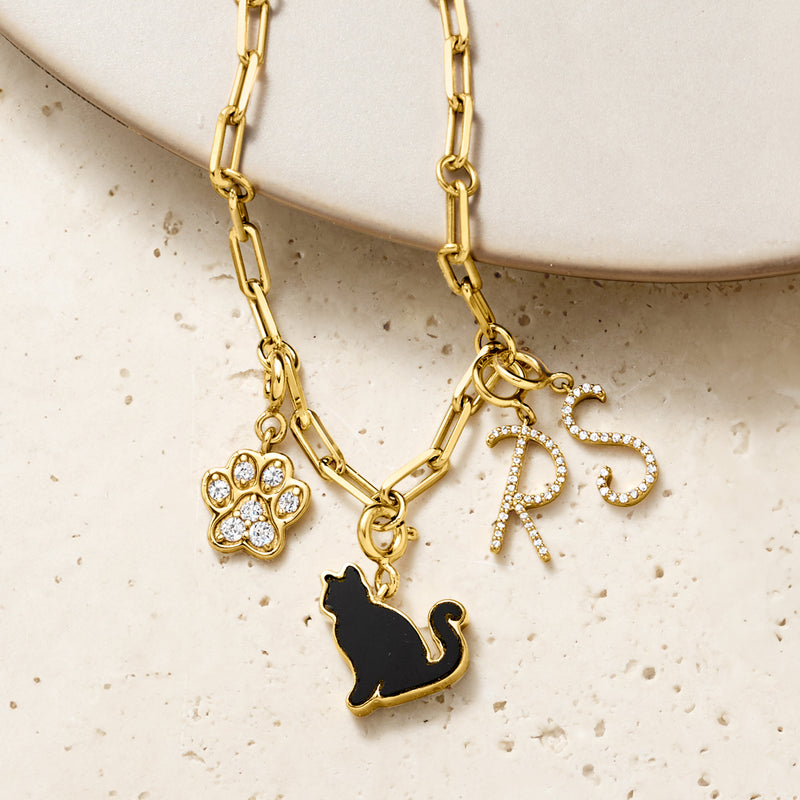 Gold-tone charm necklace with black onyx cat, flower charm, and rhinestone R