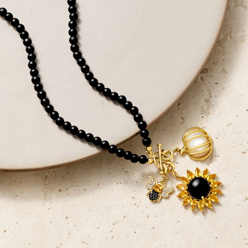Black beaded necklace with gold-tone flower charm; black round center and yellow petal stones