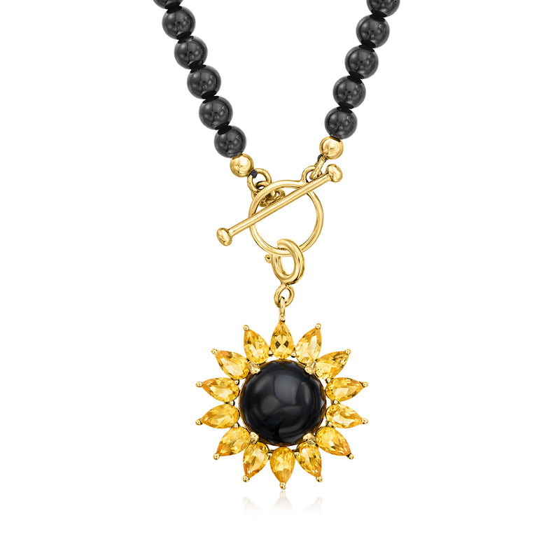 Gold-tone flower charm with black round center and yellow petal stones on clasped bead strand