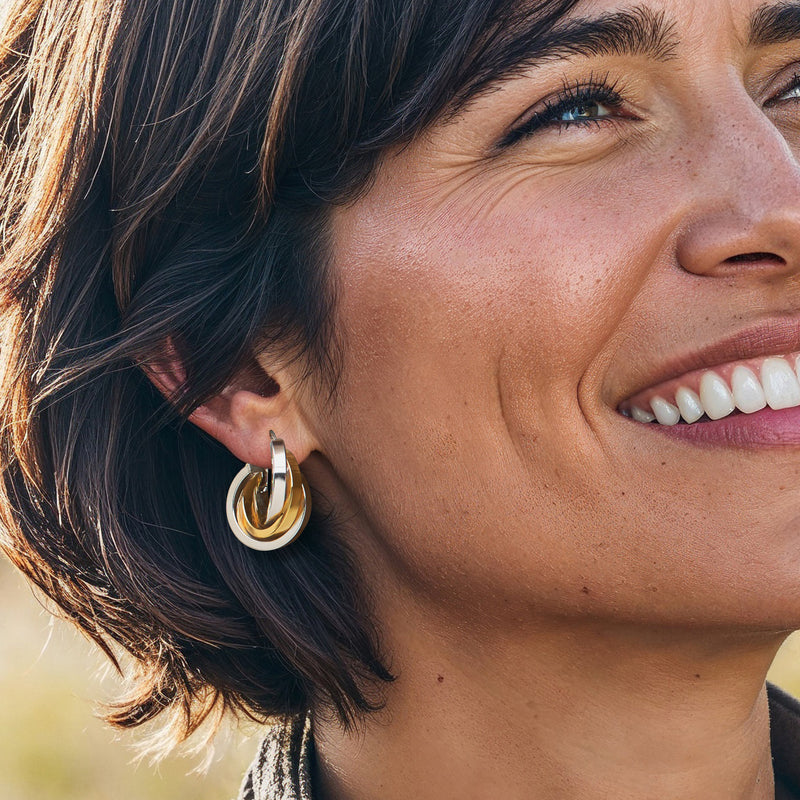 Interlocking hoop earrings with silver frame and gold accent, worn by model