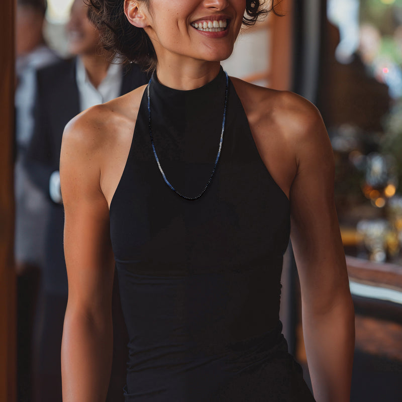 Sapphire bead necklace with blue beads, worn around neck over sleeveless black top