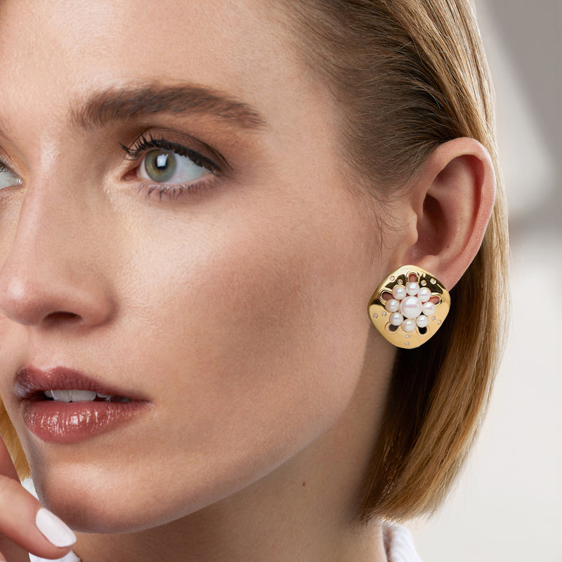 Gold-tone pearl cluster earrings with clear stones worn on ear
