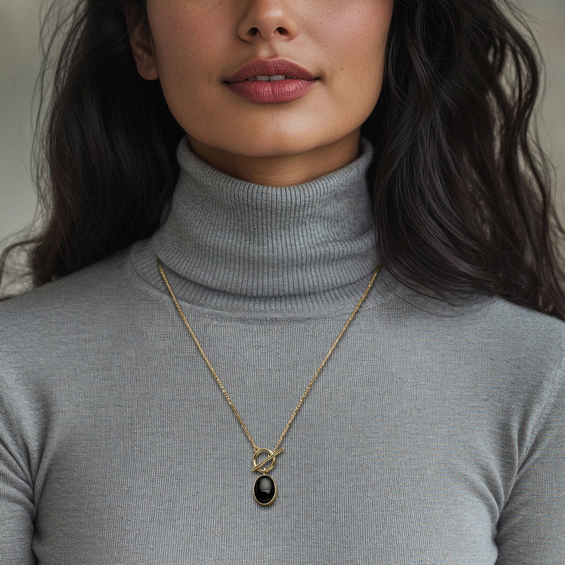 Gold onyx pendant necklace on a model with a turtleneck, oval black drop