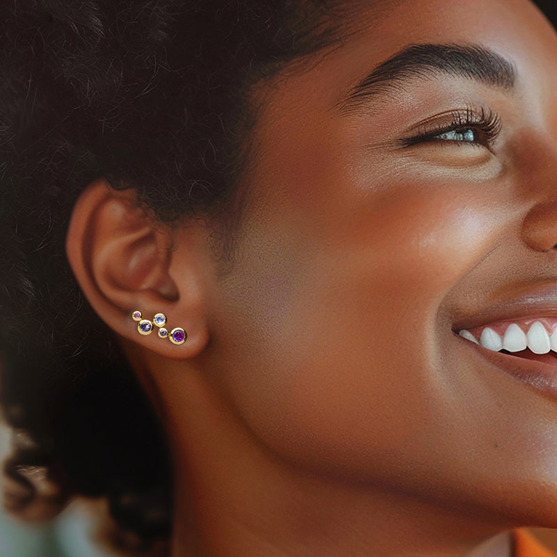 Gold ear climber earrings with purple and blue round stones worn on ear