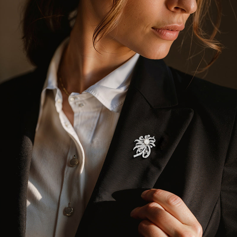 Cultured pearl and diamond floral lapel pin on a dark blazer