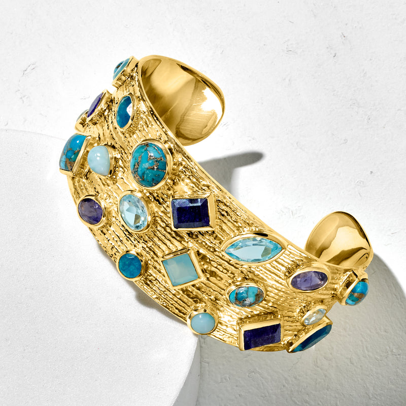 Gold cuff bracelet with blue oval and square gems and purple accents