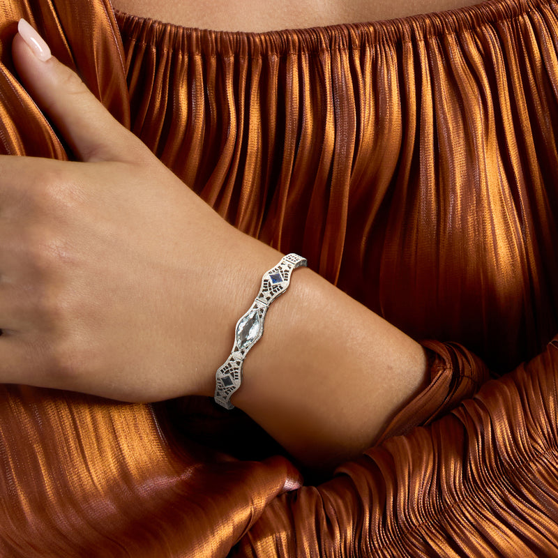 Aquamarine filigree bracelet on wrist with oval center stone and blue accent sapphires.