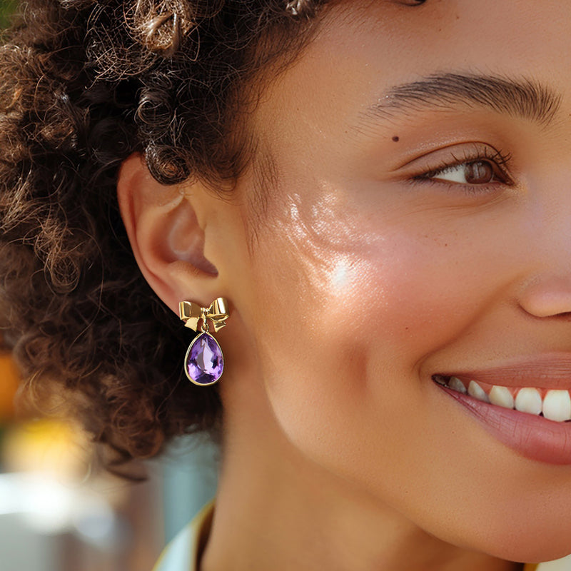 Amethyst bow drop earrings worn, yellow gold bows with purple teardrop stone drops