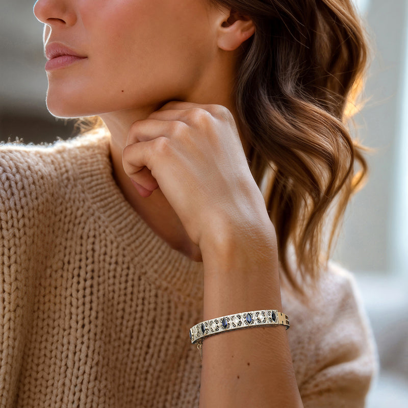 Blue-stone filigree bangle bracelet with diamond-like accents on wrist