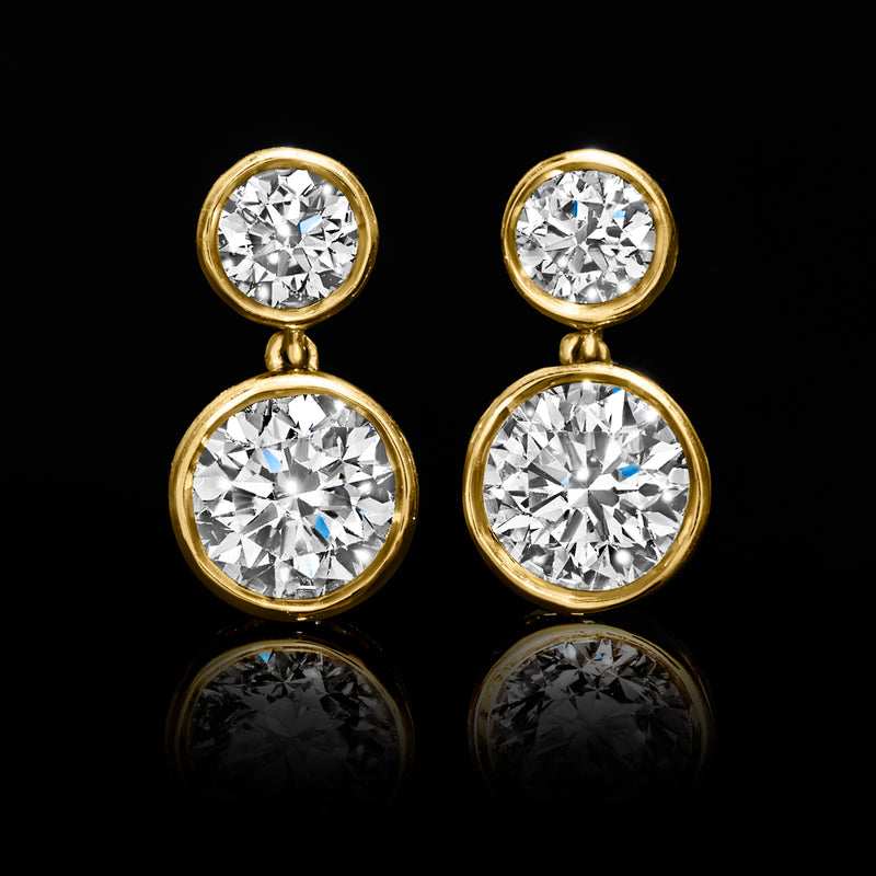 Close-up of 14kt yellow gold bezel-set round diamond drop earrings, top and larger bottom