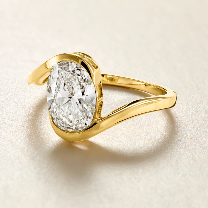 Asymmetrical yellow gold ring with oval diamond center and flowing shoulders