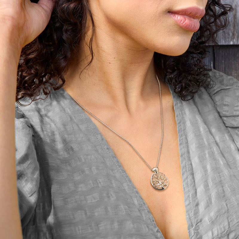 Sea life pendant necklace worn on a chain; round coral pendant with shell detail