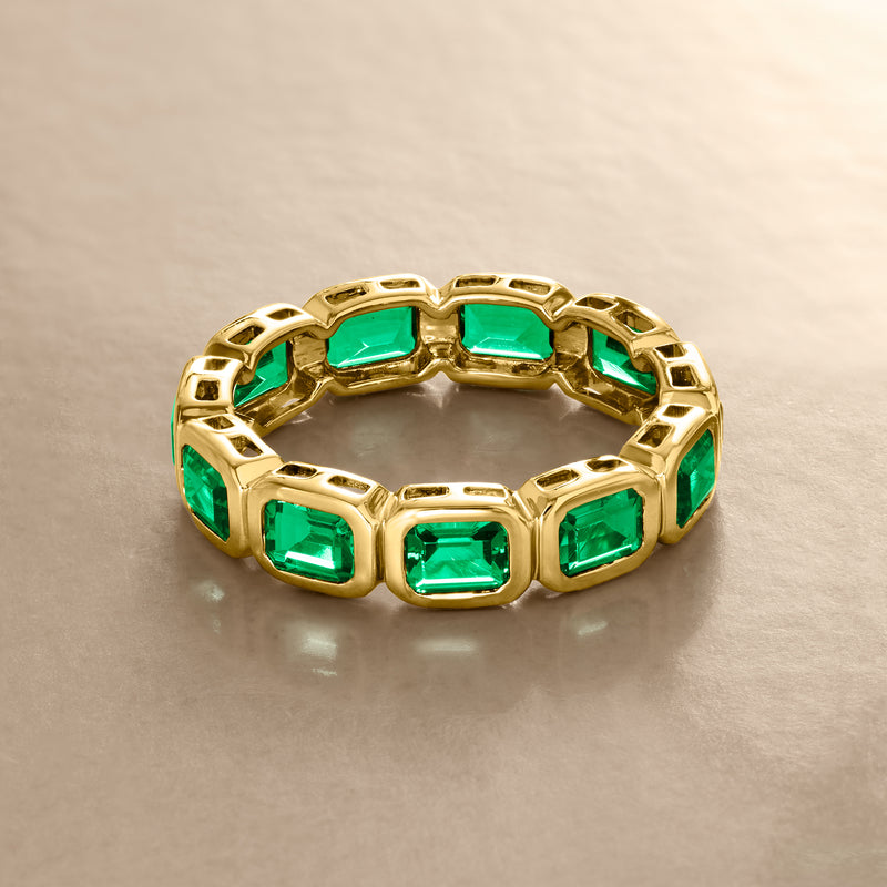 Gold eternity ring with a full row of emerald-cut green gemstones