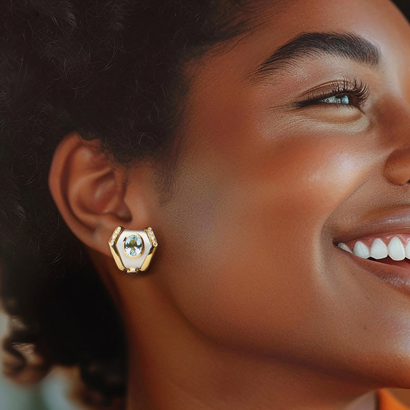 Two-tone gold geometric stud earrings on model with blue topaz and diamond accents