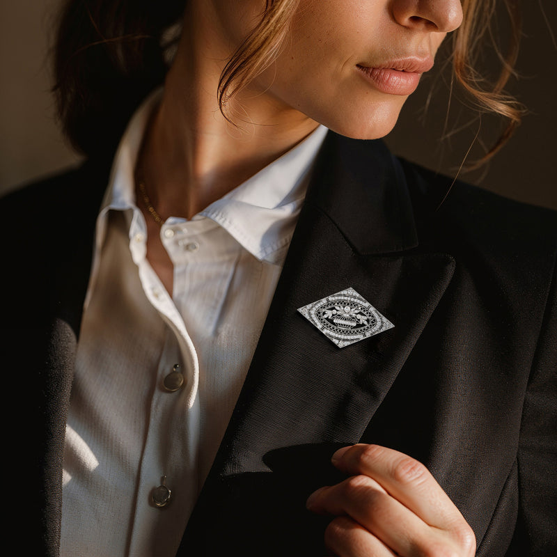 Diamond filigree pin on a blazer lapel, platinum-toned with ornate oval center