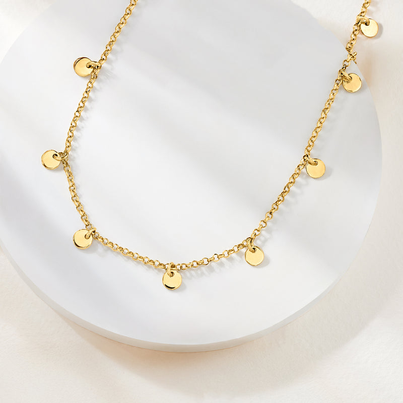 Gold disc station necklace on round display, thin chain with small round charm discs