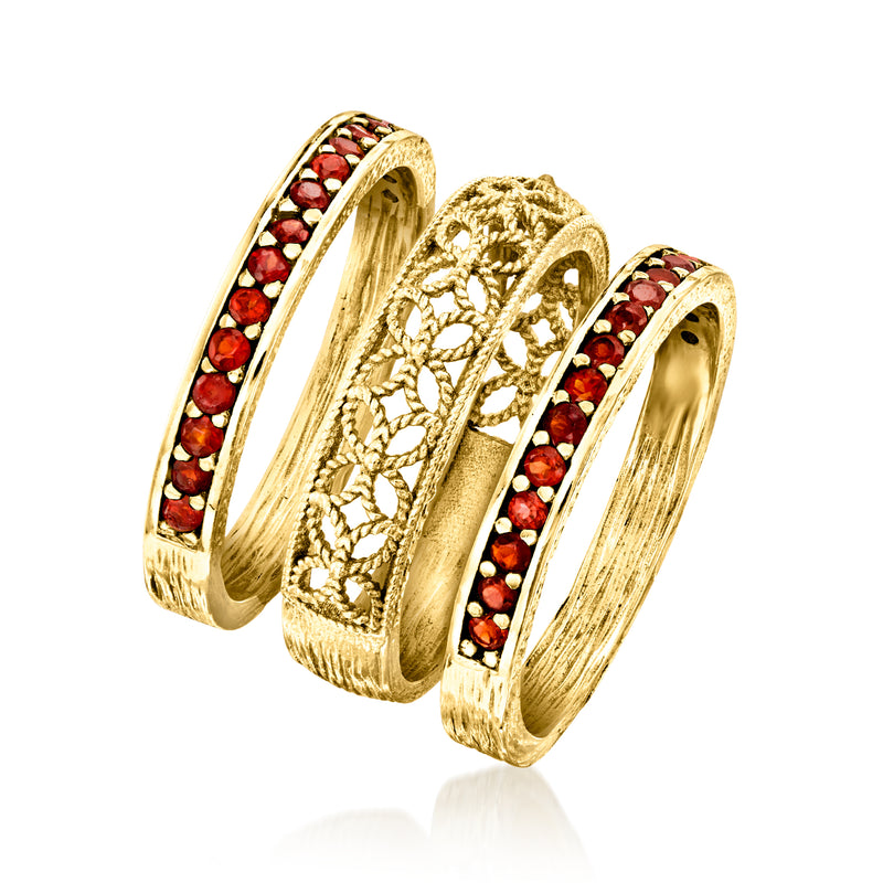 Two side-by-side gold-tone rings with red garnet stones and raised scroll pattern