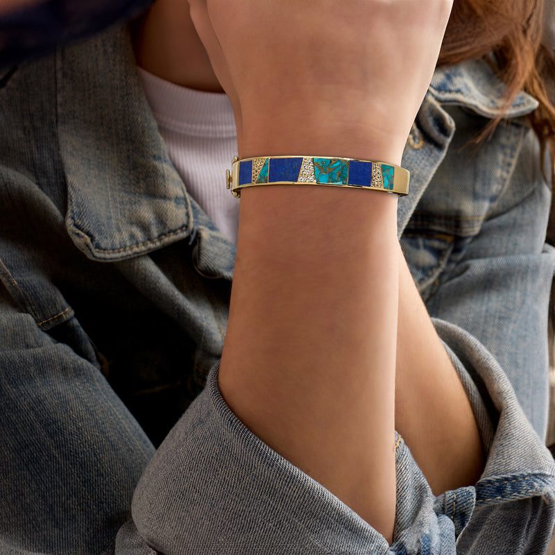 Gold-tone bracelet on wrist with blue and turquoise inlaid stones and white accents