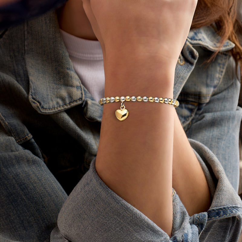 Silver and gold bead bracelet with small heart charm on wrist