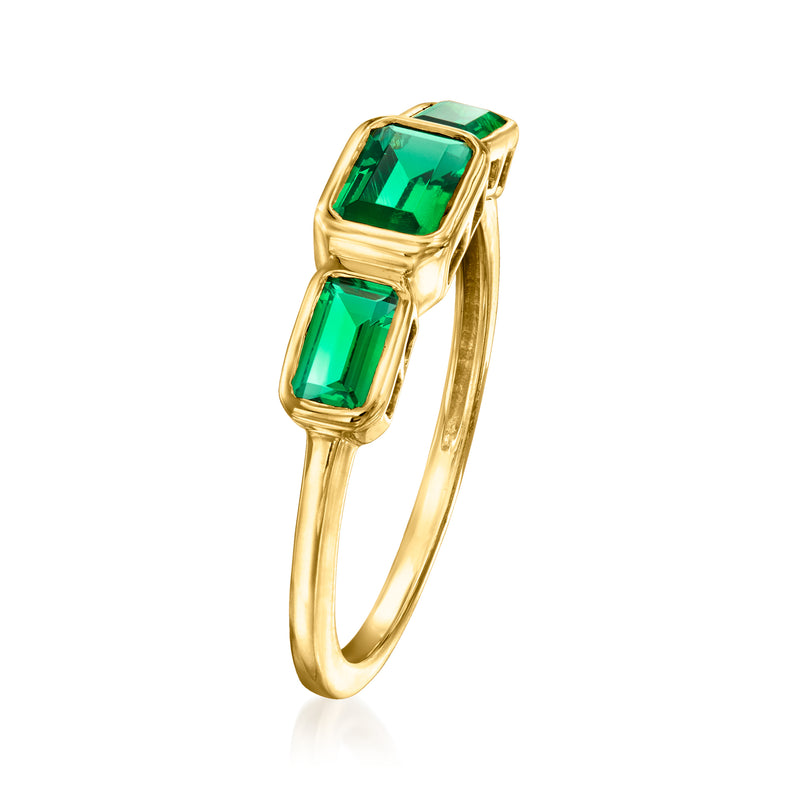 Gold three-stone ring side view with emerald-cut green gems