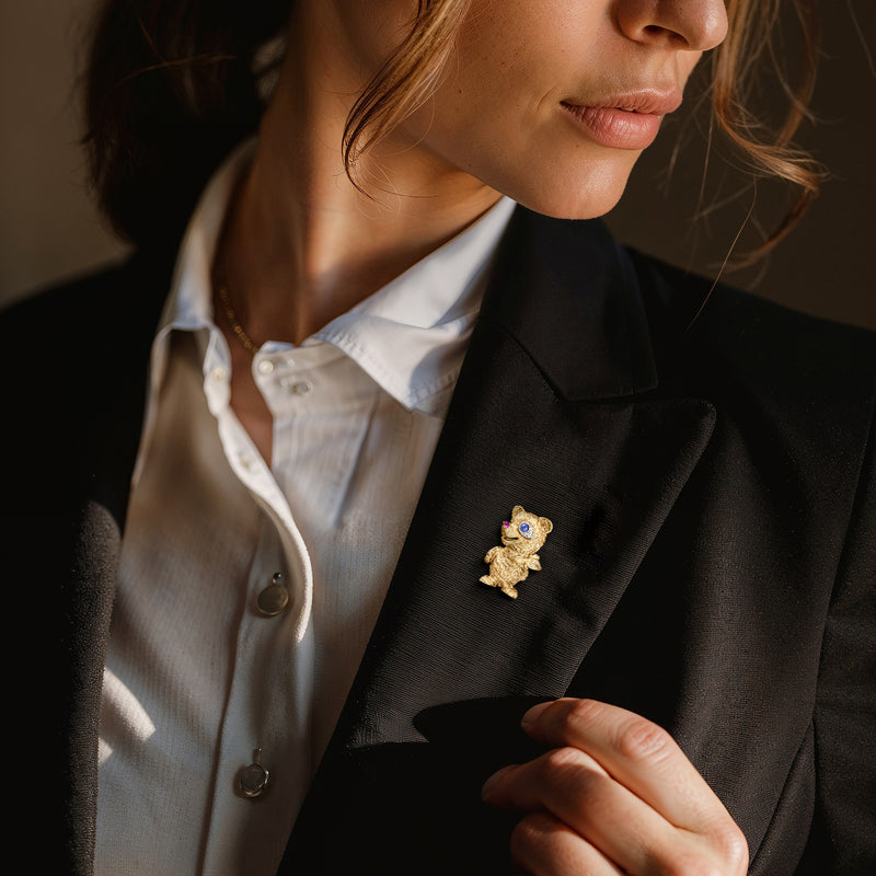 Teddy bear lapel pin in yellow gold with blue center and purple ruby