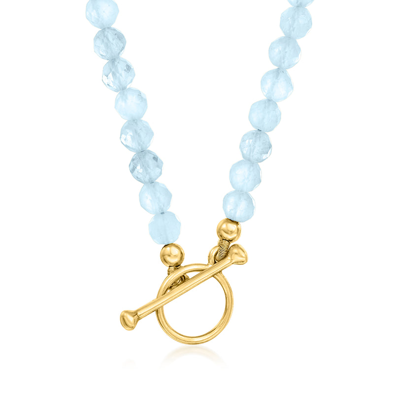 Aquamarine bead charm necklace with gold toggle clasp and bead strand tassel details.
