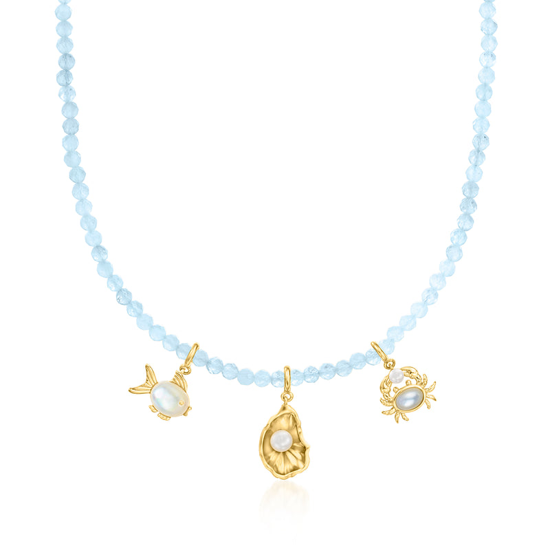Aquamarine bead necklace with gold charm accents: bee, sun, and coin-like pendant.