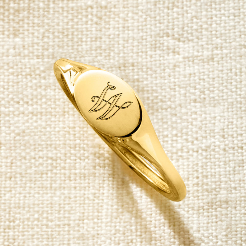 10kt yellow gold signet ring with monogram initials on oval face, angled view