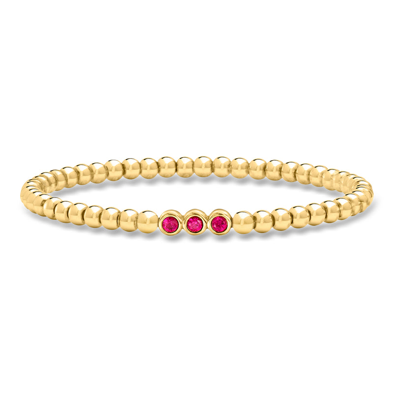 Gold beaded stretch bracelet with three round ruby accent beads in center