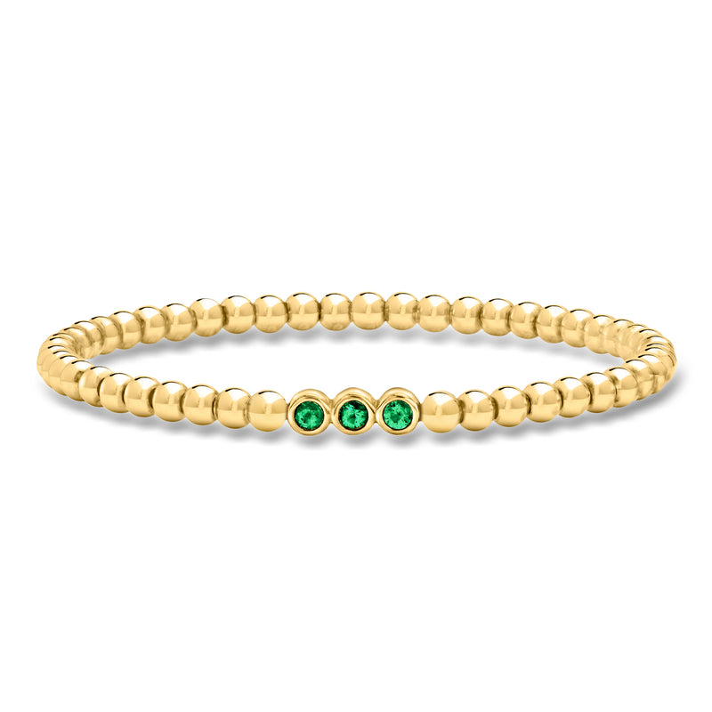Gold bead stretch bracelet with three green emerald-style stones