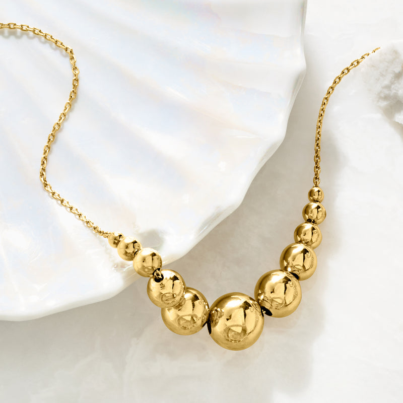Gold-tone graduated round-bead necklace with cable chain, close-up